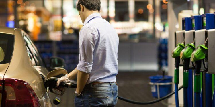 Young man fueling his car at the gas station