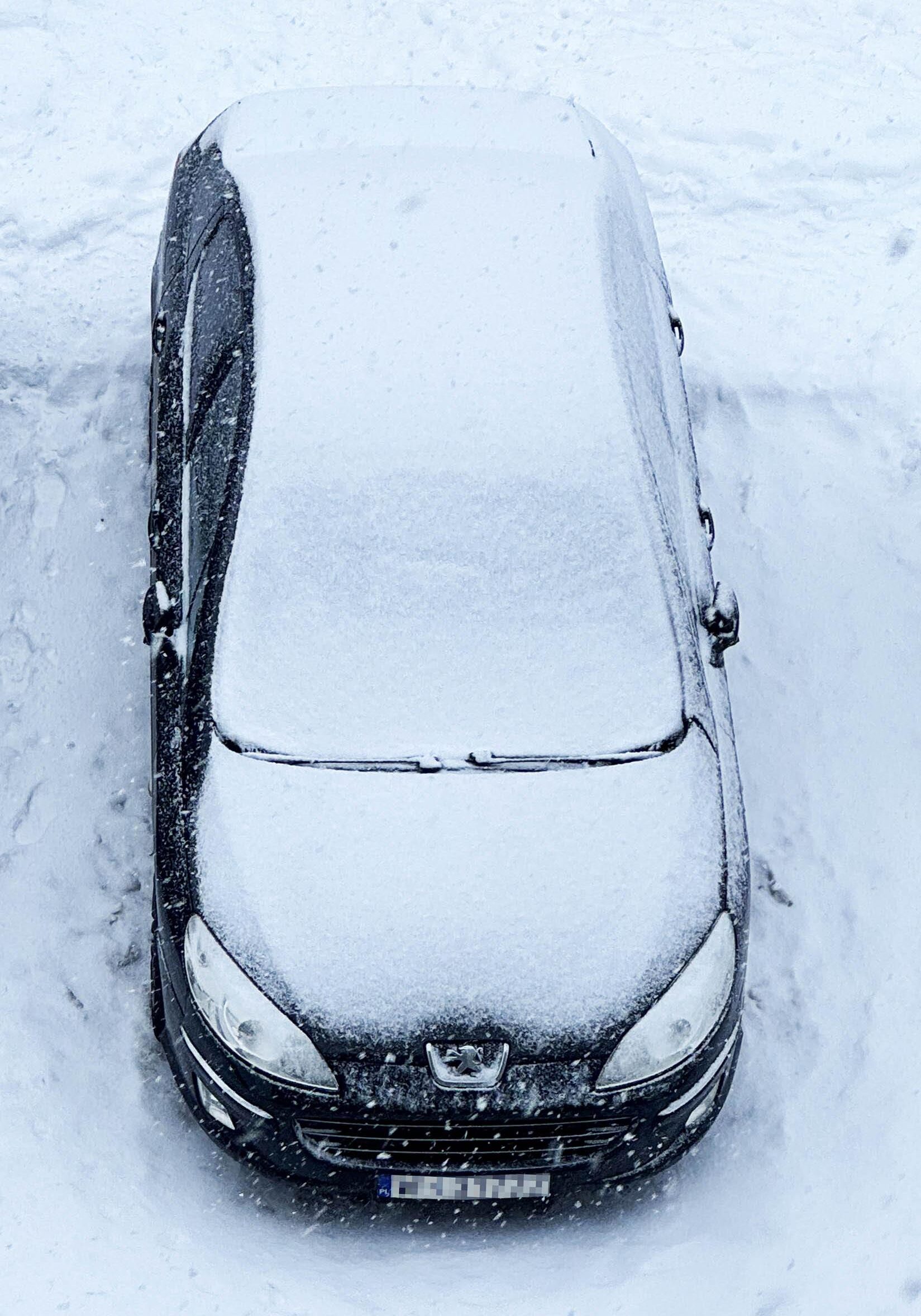 Peugeot 407 zasypany śniegiem podczas zimowego postoju